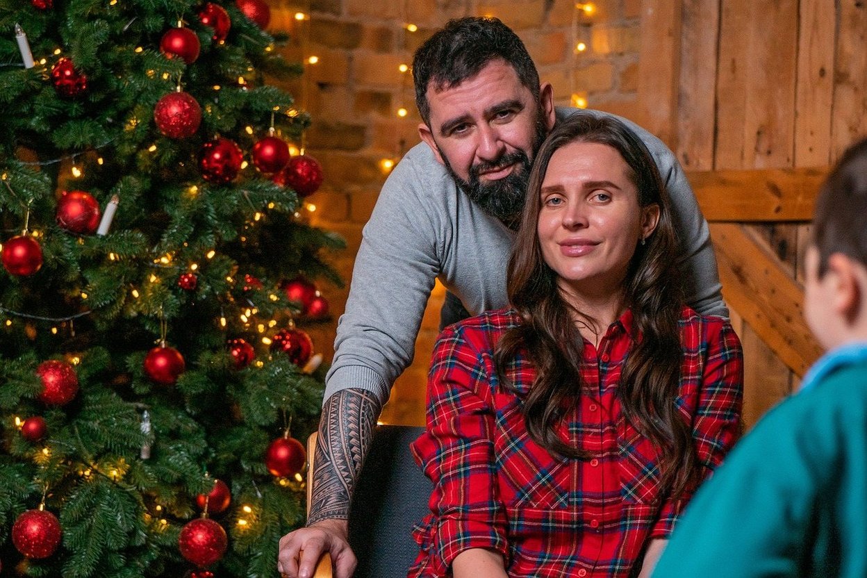 Family gathered around a decorated Christmas tree with warm lights.