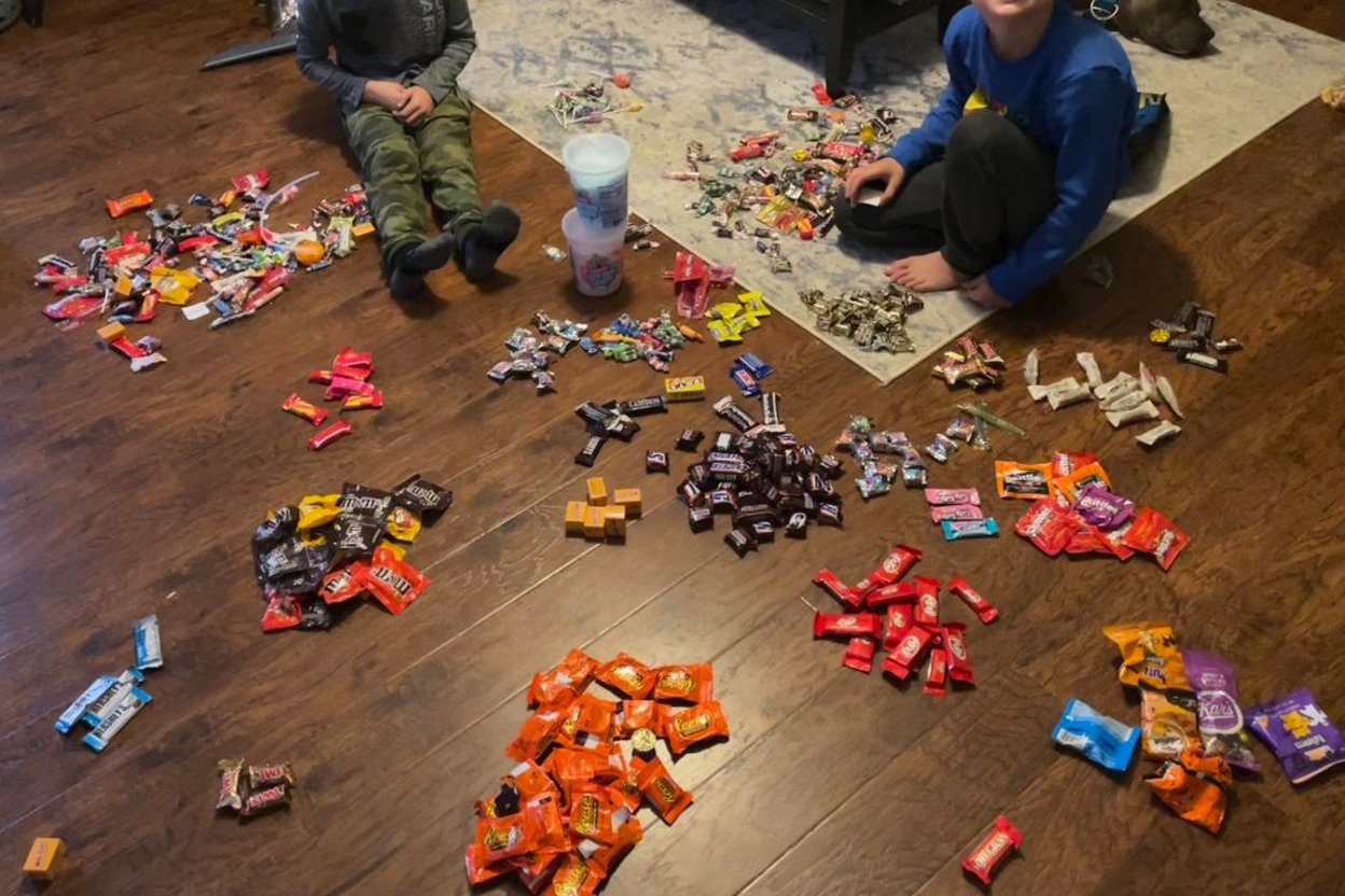 Children sorting Halloween candy into bowls on a kitchen table at home
