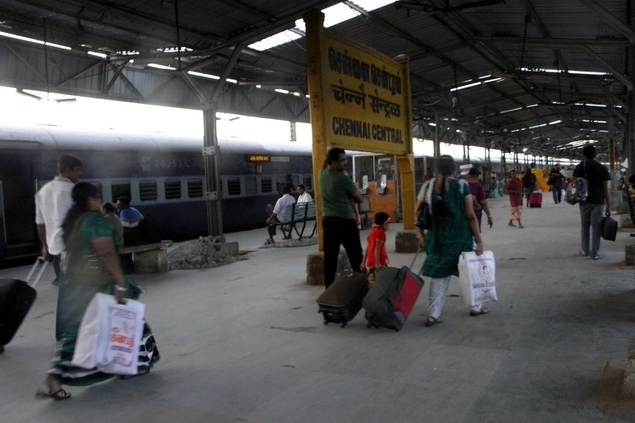 A child pulling the bags along a train platform with parents.