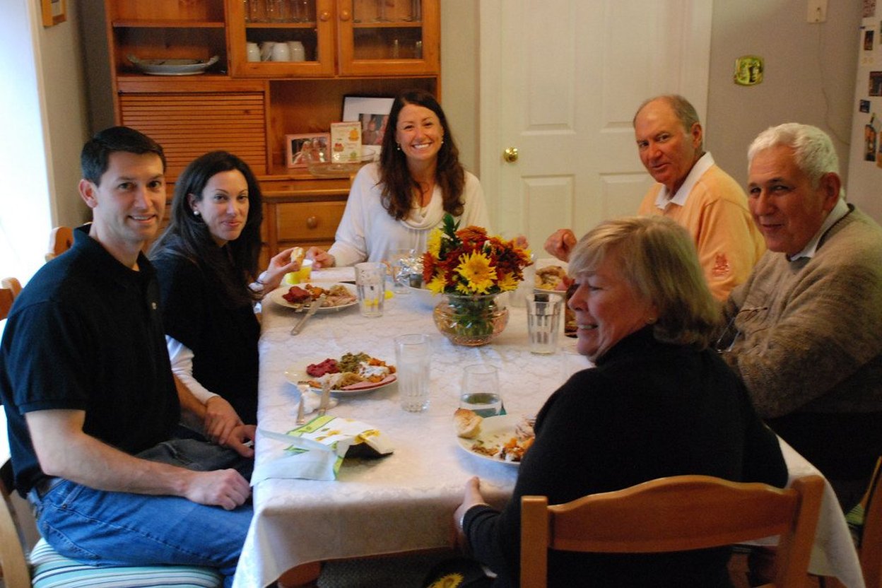 Family gathering around a dining table with food and flowers.