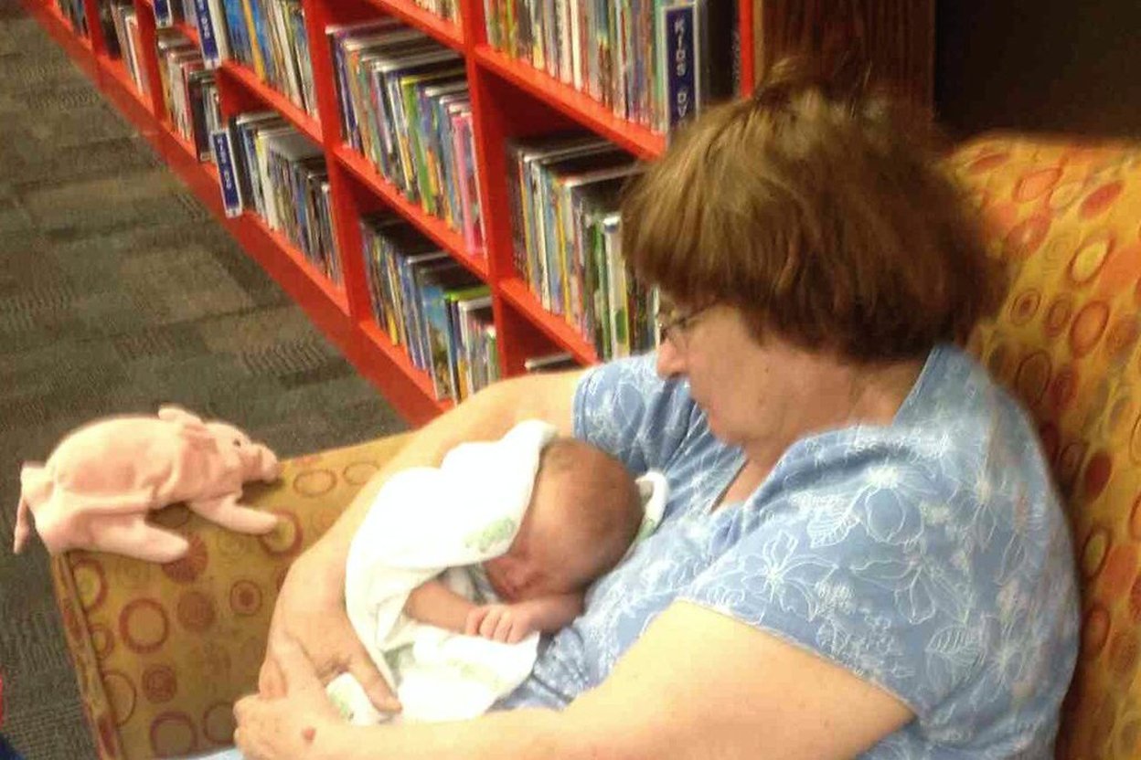 A parent sitting with a young child at a kitchen table, reading a picture book together in a calm, warmly lit home.
