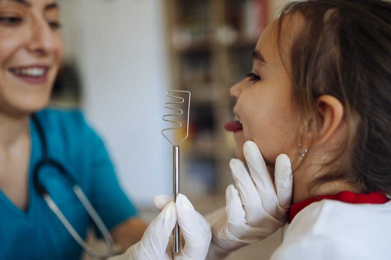 A doctor examining a smiling child during a checkup.