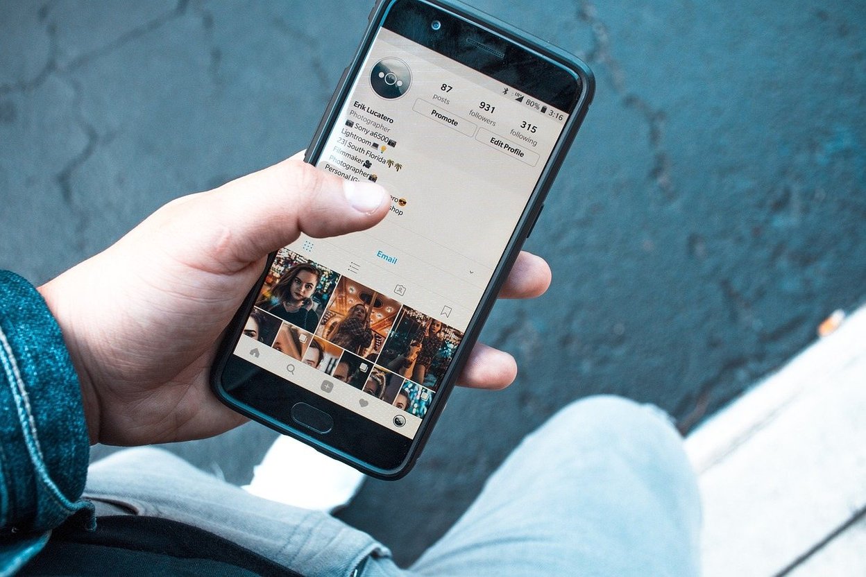 A hand holding a phone open to an Instagram profile.